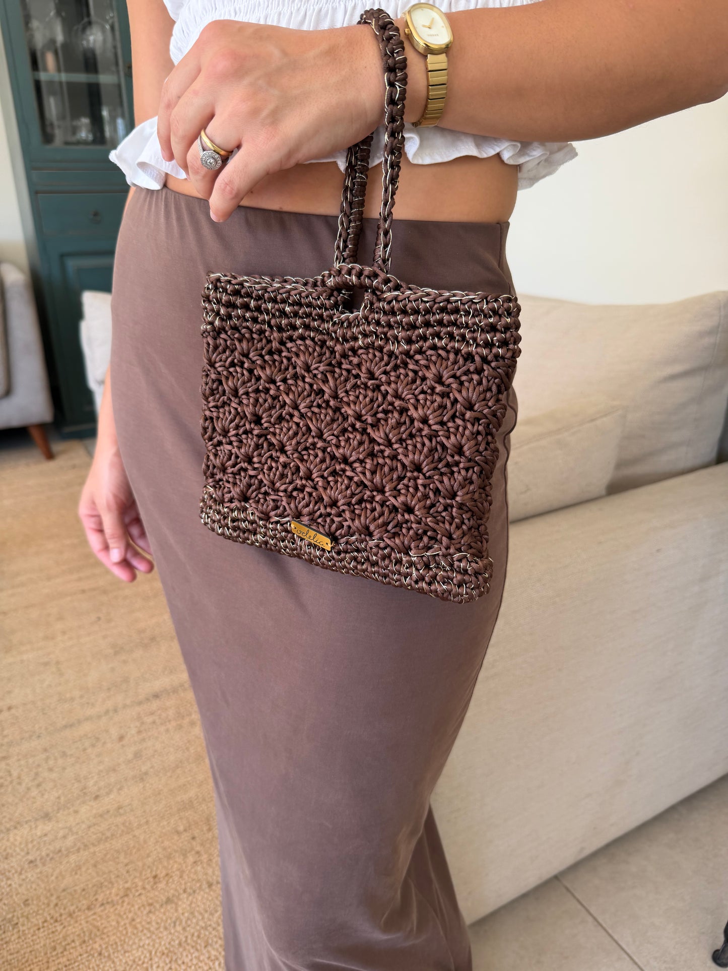 Bolso tejido de color marrón con detalles dorados, ideal para eventos